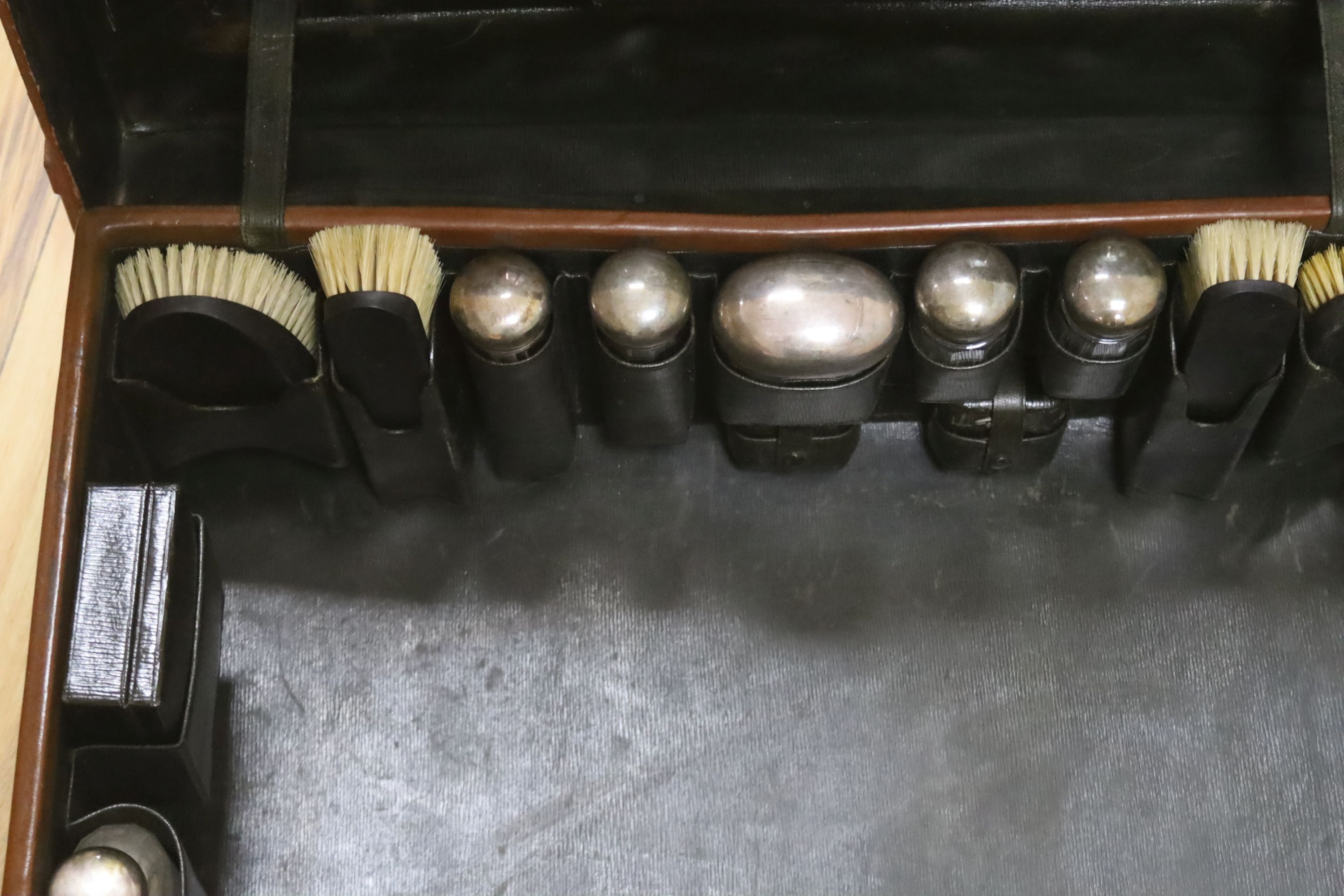 A gentleman's brown leather cased silver travelling vanity set, with silver lidded bottles interior, initialled HS
